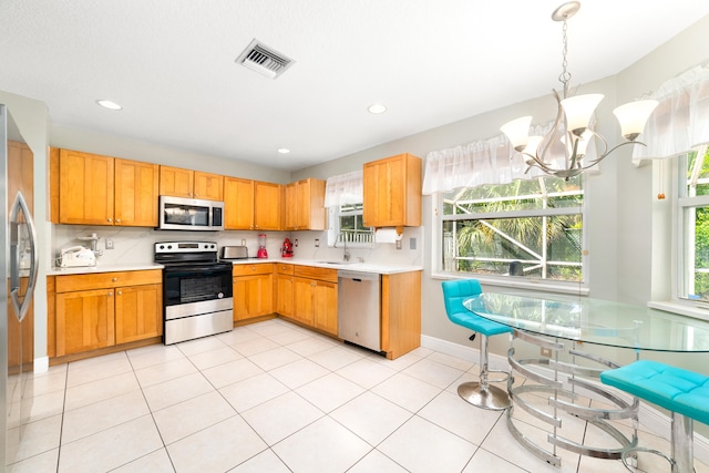 kitchen featuring stainless steel appliances, a notable chandelier, light tile patterned flooring, and hanging light fixtures