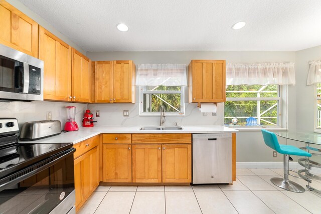 kitchen featuring sink, a textured ceiling, light tile patterned flooring, and stainless steel appliances