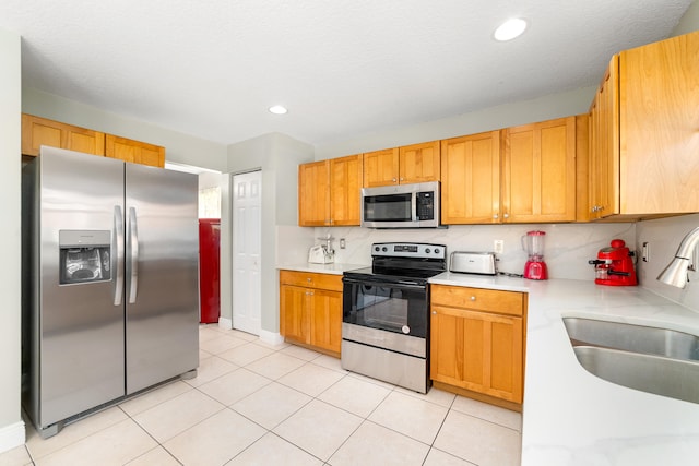 kitchen featuring sink, stainless steel appliances, light tile patterned flooring, and decorative backsplash