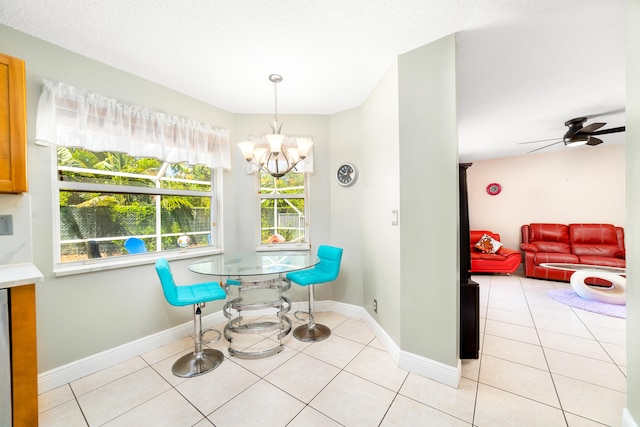 tiled dining room featuring ceiling fan with notable chandelier