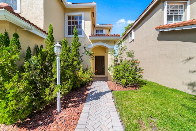 view of exterior entry with a yard