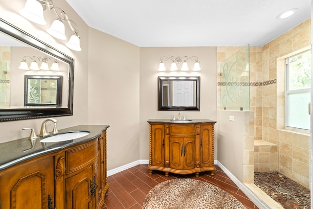 bathroom with tiled shower, dual bowl vanity, and tile patterned flooring