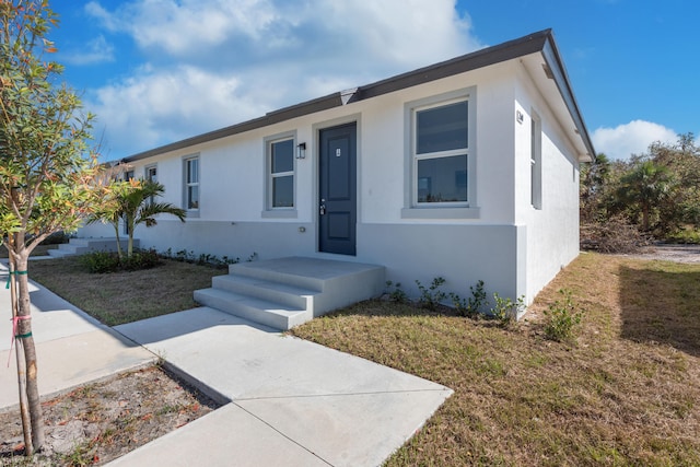 view of front of house featuring stucco siding and a front lawn