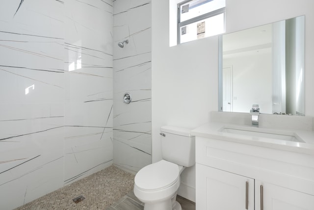 bathroom featuring tiled shower, toilet, and vanity