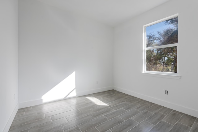 spare room with baseboards and wood finish floors