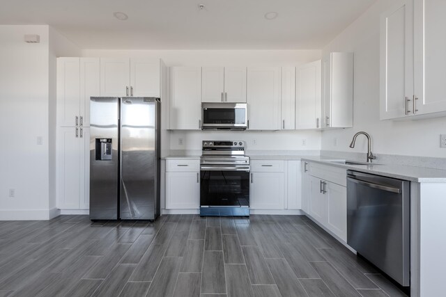 kitchen with white cabinetry, stainless steel appliances, sink, and dark hardwood / wood-style flooring