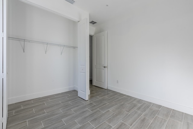 unfurnished bedroom featuring a closet, visible vents, baseboards, and wood tiled floor