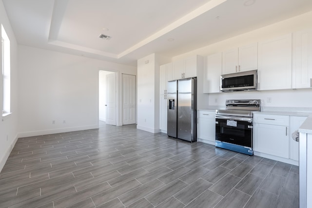 kitchen with visible vents, light countertops, appliances with stainless steel finishes, white cabinets, and a raised ceiling