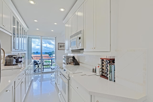 kitchen featuring expansive windows, decorative backsplash, white cabinetry, light stone countertops, and white appliances