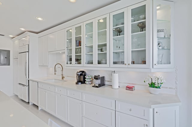 bar with sink, paneled built in refrigerator, decorative backsplash, white dishwasher, and white cabinets