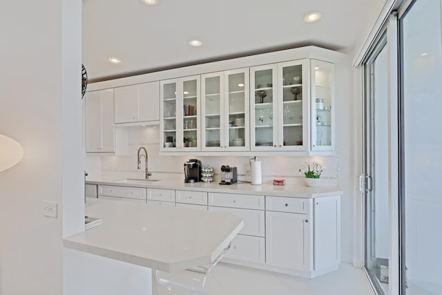 bar with sink, light tile patterned flooring, white cabinetry, and backsplash