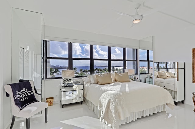 bedroom with a water view, ceiling fan, and multiple windows