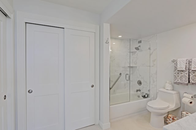 bathroom with tile patterned flooring, toilet, and bath / shower combo with glass door