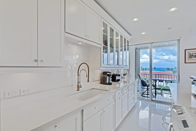 kitchen with sink, white cabinetry, light stone counters, decorative backsplash, and light tile patterned floors