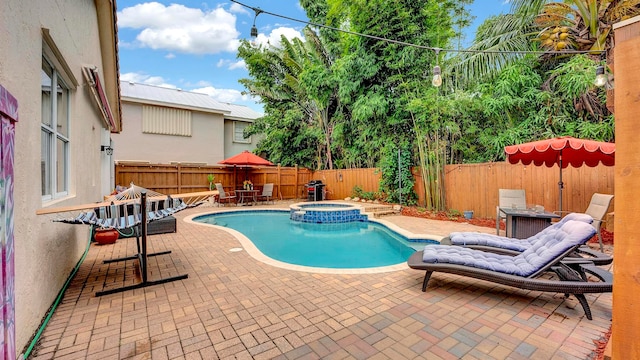 view of swimming pool featuring an in ground hot tub and a patio