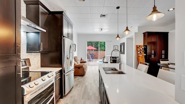 kitchen featuring decorative light fixtures, wall chimney exhaust hood, sink, electric range oven, and stainless steel fridge with ice dispenser