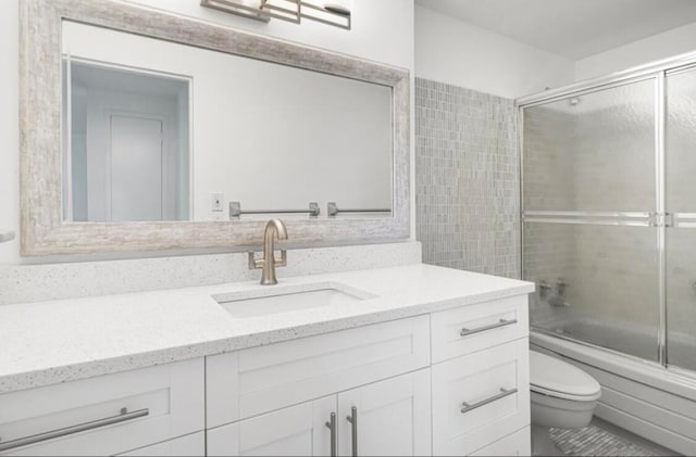 full bathroom featuring toilet, vanity, and enclosed tub / shower combo