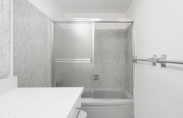 full bathroom featuring enclosed tub / shower combo, vanity, and toilet