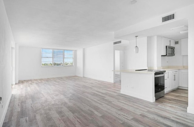 interior space with light hardwood / wood-style floors, appliances with stainless steel finishes, kitchen peninsula, and white cabinets