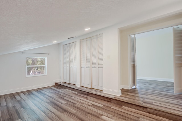 interior space featuring light wood-type flooring, a textured ceiling, and vaulted ceiling