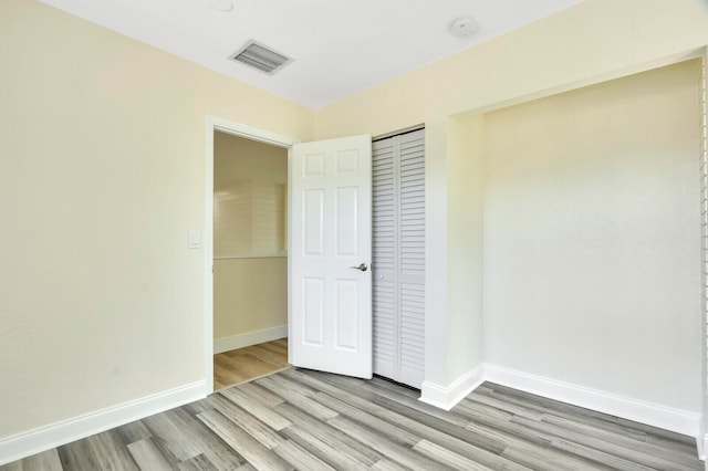 unfurnished bedroom with light wood-type flooring and a closet