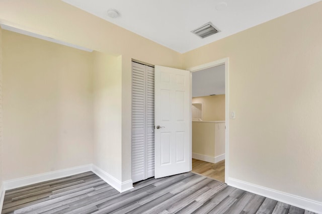 unfurnished bedroom with light hardwood / wood-style flooring and a closet