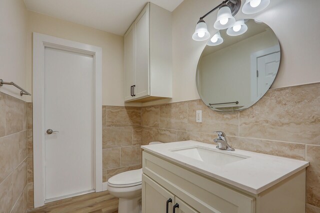 bathroom with tile walls, wood-type flooring, vanity, and toilet