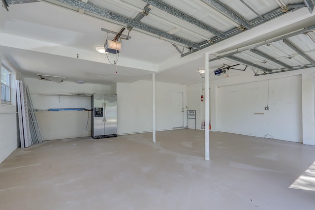 garage with stainless steel fridge and a garage door opener