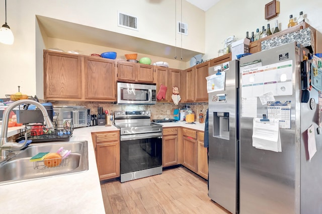 kitchen featuring visible vents, stainless steel appliances, light countertops, pendant lighting, and a sink