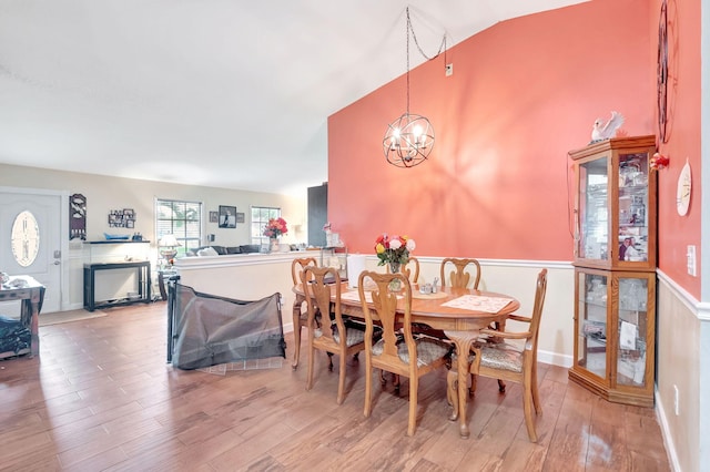 dining room with high vaulted ceiling, wood finished floors, and an inviting chandelier