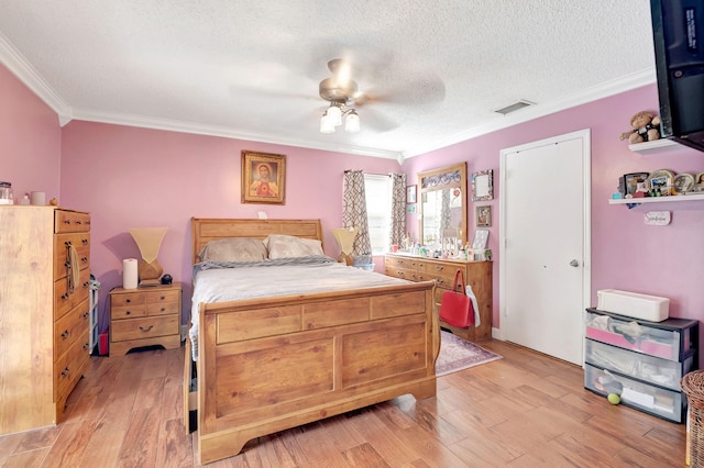 bedroom featuring visible vents, a ceiling fan, ornamental molding, a textured ceiling, and light wood-style floors