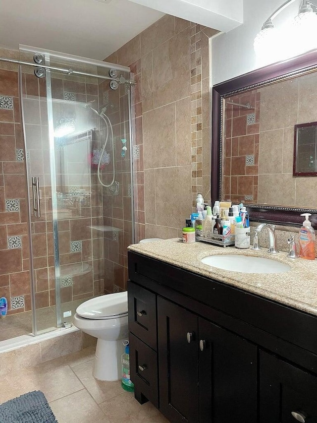 full bathroom with toilet, tile patterned flooring, vanity, a shower stall, and tile walls