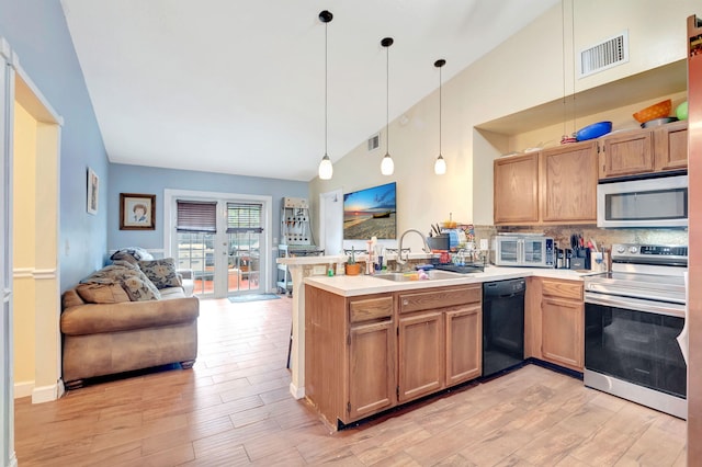 kitchen featuring open floor plan, decorative light fixtures, stainless steel appliances, light countertops, and a sink