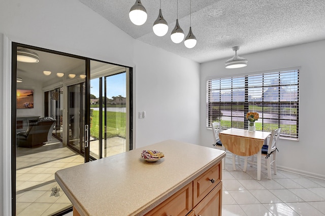 kitchen with plenty of natural light, a textured ceiling, a center island, and light tile patterned floors