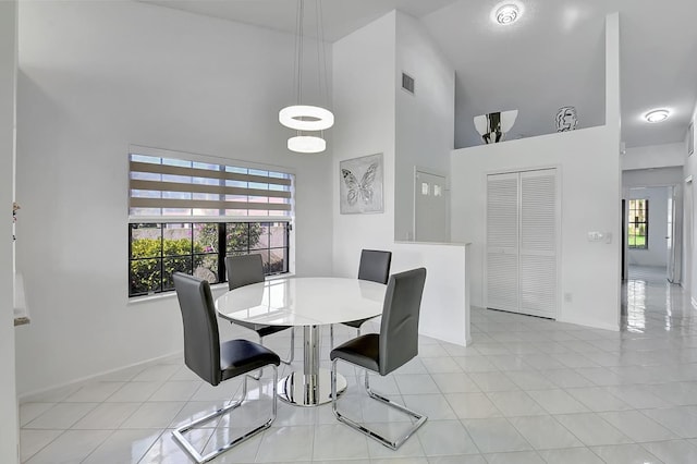 dining space with light tile patterned flooring and high vaulted ceiling