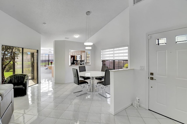 entryway with a textured ceiling, high vaulted ceiling, a healthy amount of sunlight, and light tile patterned floors