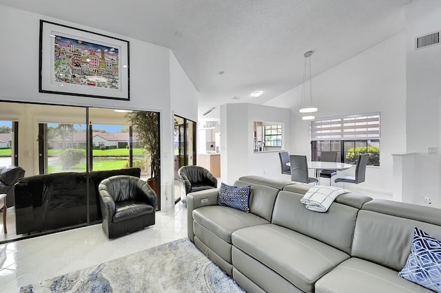 living room featuring a textured ceiling, high vaulted ceiling, and light tile patterned floors