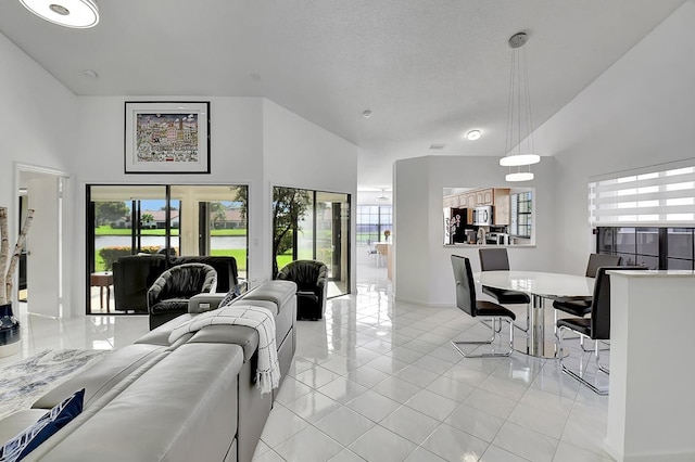 living room with a high ceiling, a textured ceiling, and light tile patterned floors