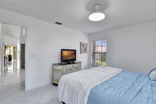 bedroom featuring a textured ceiling, vaulted ceiling, and light tile patterned flooring