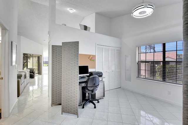 office area with light tile patterned floors, high vaulted ceiling, and a textured ceiling