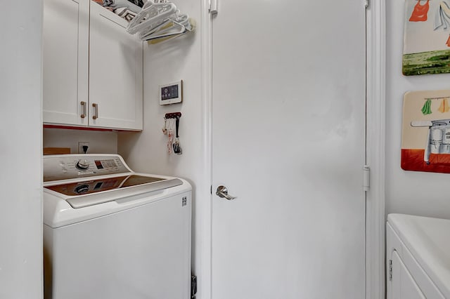 laundry area with washing machine and clothes dryer and cabinets