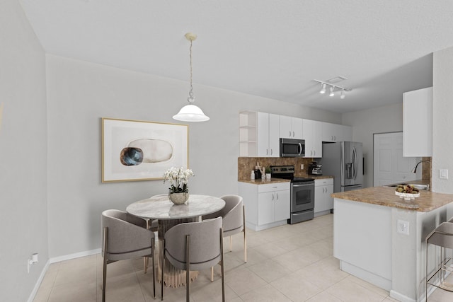 kitchen featuring stainless steel appliances, white cabinets, pendant lighting, and sink