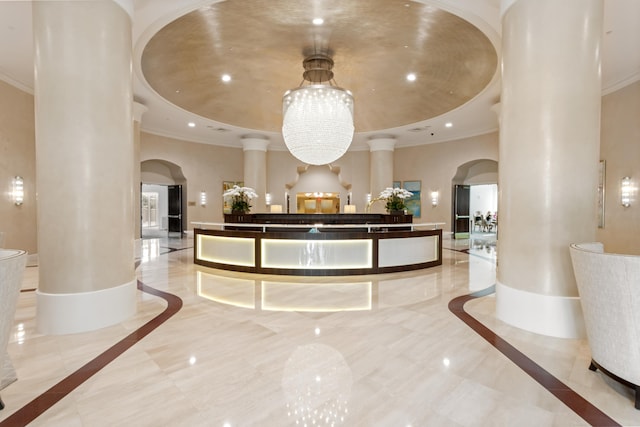 reception area featuring ornate columns and an inviting chandelier