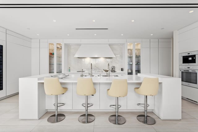 kitchen with a breakfast bar area, a large island with sink, and white cabinets