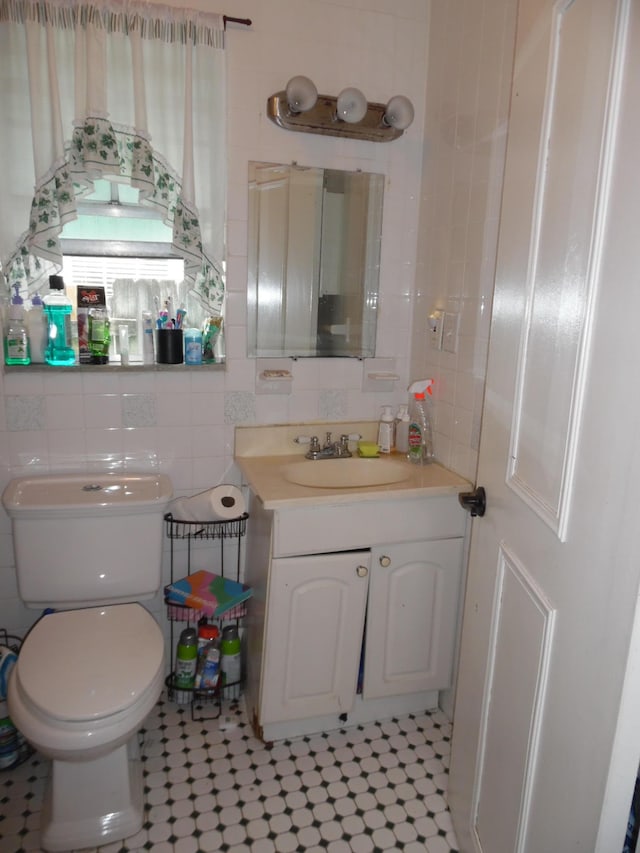 bathroom with toilet, decorative backsplash, tile walls, tile patterned floors, and vanity