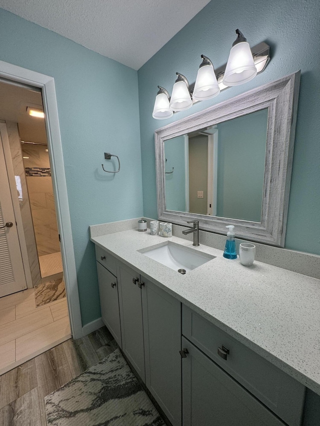 bathroom featuring a shower, vanity, wood-type flooring, and a textured ceiling