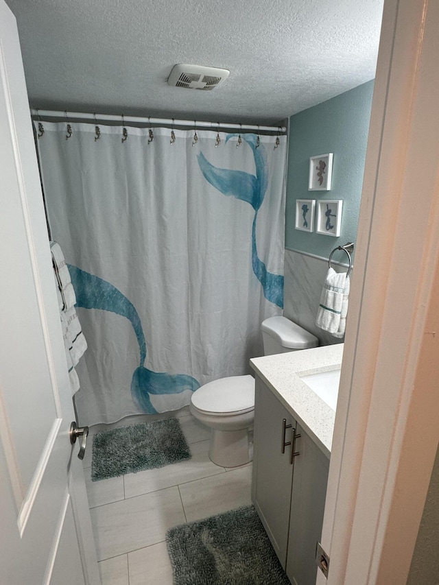 bathroom featuring vanity, a textured ceiling, and toilet