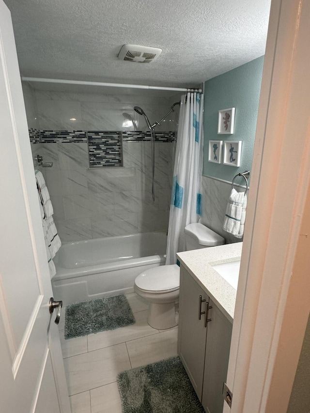 full bathroom with tile patterned floors, a textured ceiling, toilet, shower / bath combo with shower curtain, and vanity