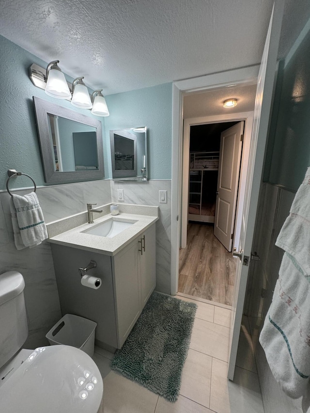 bathroom with vanity, a textured ceiling, hardwood / wood-style flooring, and toilet