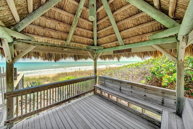 deck featuring a gazebo, a water view, and a beach view